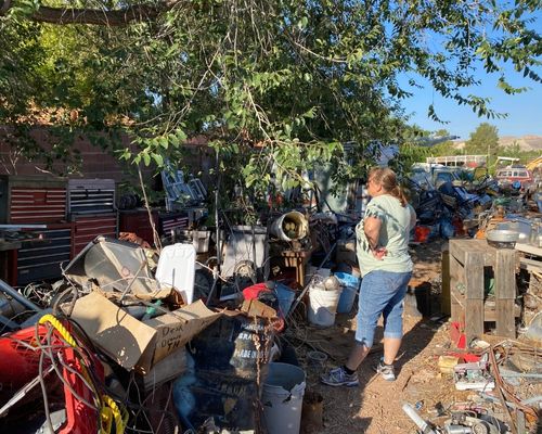Rescuer stands in junk yard with piles of trash looking for injured kitten. 
