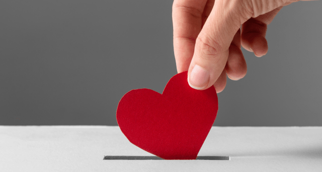 Hand dropping a heart into a donation box